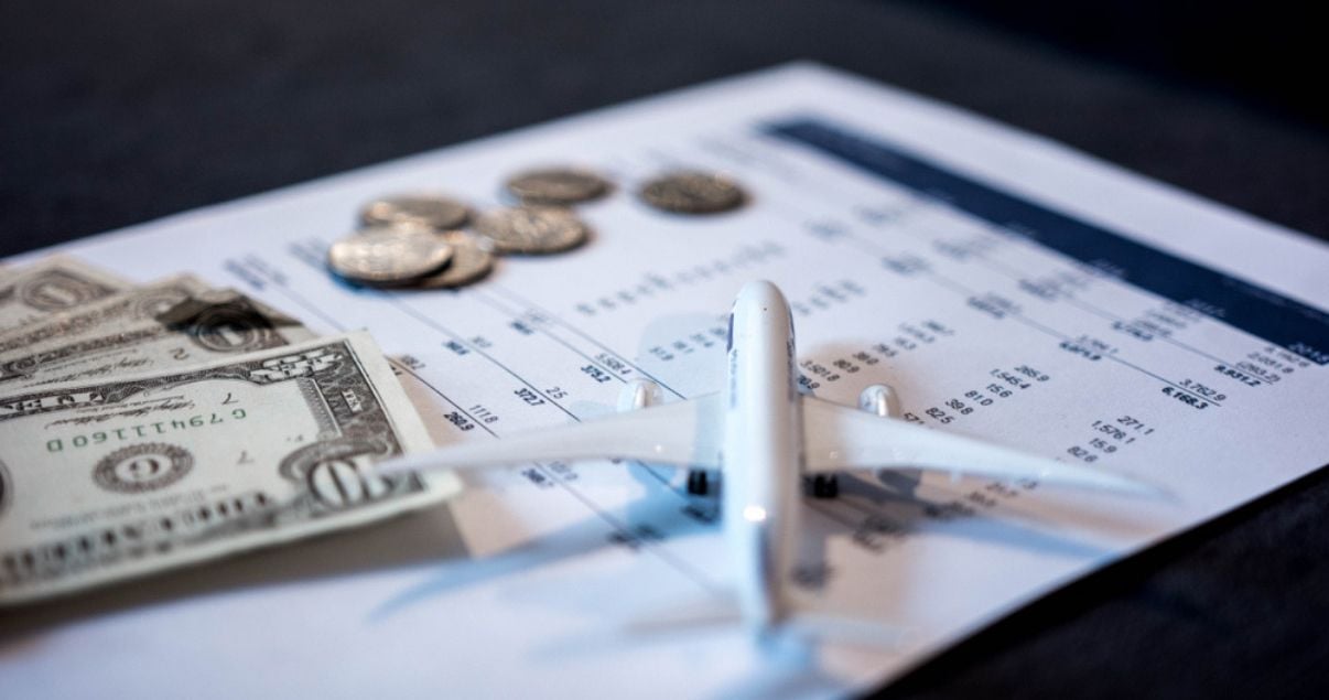 Avion de juguete sobre tabla con numeros junto a billetes y monedas de dolares, para simbolizar la rentabilidad que se consigue gracias al revenue management