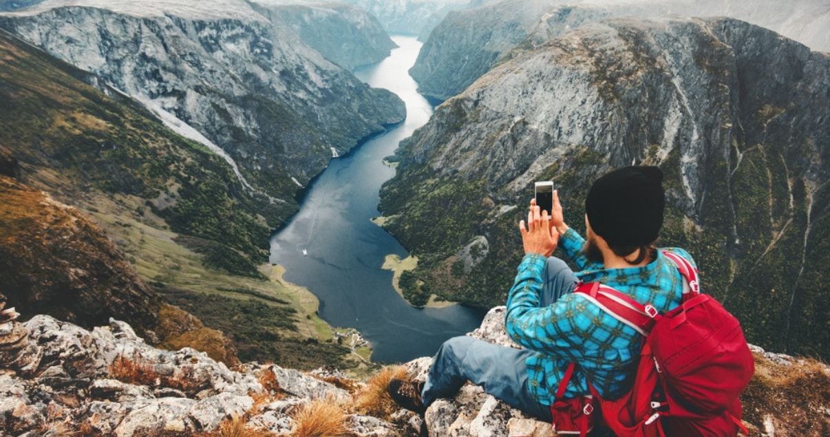 Postal de una selfie un joven adulto hombre millennial que viaja solo uno de los huespedes de un hotel ubicado en Noruega cercano a este fiordo