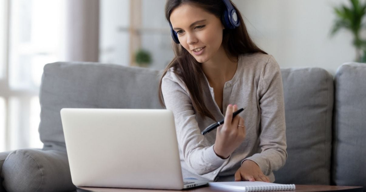 Mujer joven adulta de tez triguena mirando a la pantalla de su laptop en medio de una videollamada porque esta disenando una nueva politica de gestion de reservas hoteleras para evitar cancelaciones futuras