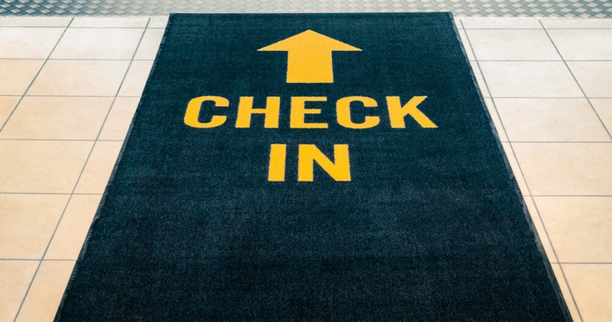Alfombra azul con letras amarillas que dicen check in y apuntan al ingreso de un hotel que implementa revenue management