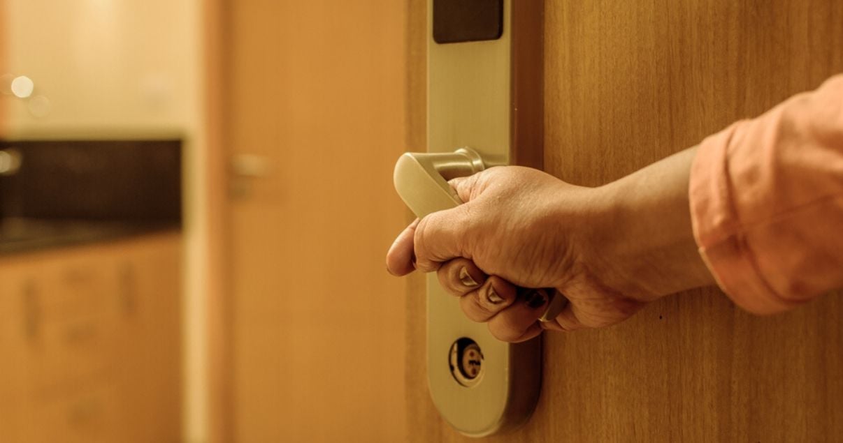 Primer plano de mano de hombre joven adulto en picaporte electrico de puerta de acceso a habitacion de un hotel que aplica revenue management